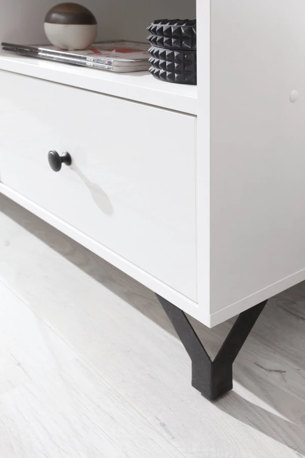 Detailansicht weißer Schrank mit rundem schwarzem Griff und filigranem Metallfuß.