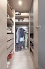 Gut organisierter begehbarer Kleiderschrank in heller Holzoptik mit vielen Regalfächern.