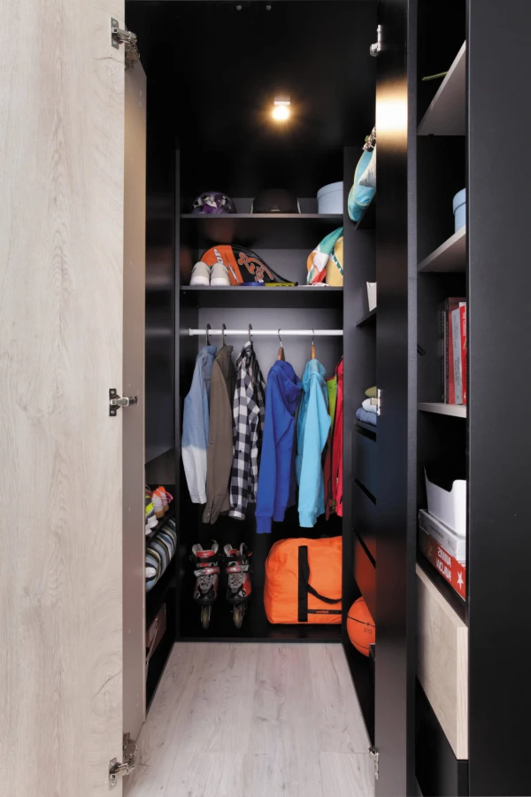 Beleuchteter begehbarer Eckkleiderschrank mit viel Platz für Kleidung und Sportausrüstung.