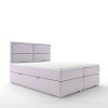 Hellviolettes Boxspringbett mit rechteckig gestepptem Kopfteil, freigestellt auf weiß.