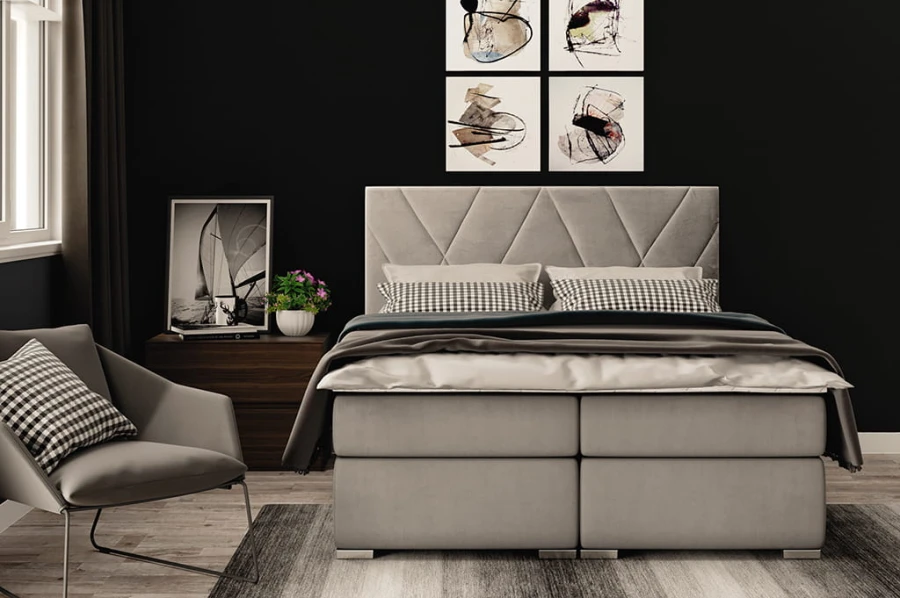 Graues Boxspringbett in modernem Schlafzimmer-Ambiente mit dunkler Wand.