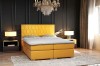 Gelbes Boxspringbett mit dekorativem Waben-Kopfteil in einem eleganten dunklen Raum.