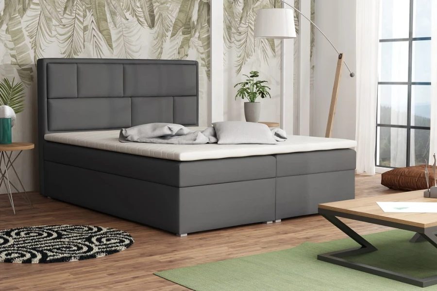 Anthrazitfarbenes Boxspringbett mit elegantem Kopfteil und weißem Topper im Schlafzimmer.