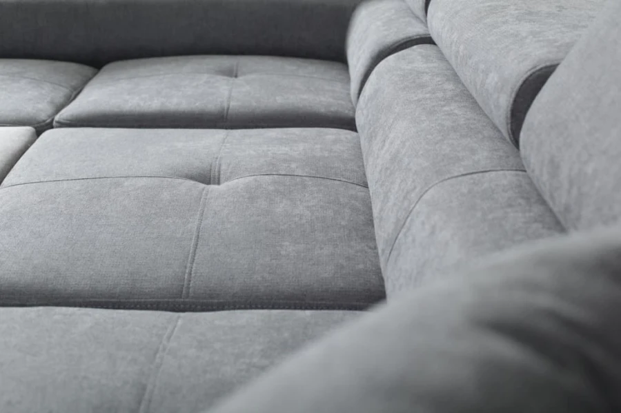 Stoffstruktur und Steppung eines grauen Polstersofas in der Nahaufnahme.