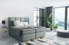 Modernes salbeigrünes Boxspringbett in hellem Schlafzimmer mit großen Fenstern.
