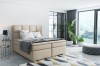 Stilvolles beiges Boxspringbett im modernen Schlafzimmer mit viel Tageslicht.