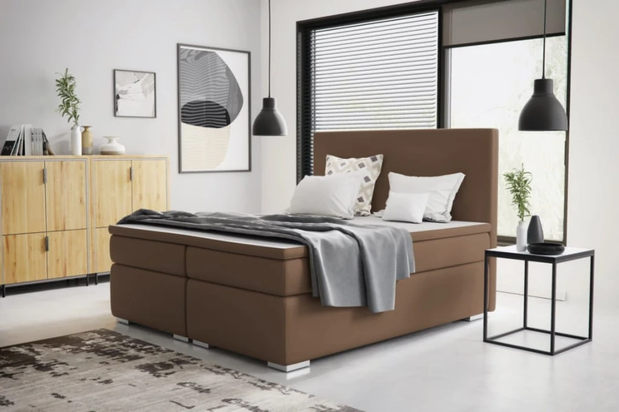 Modernes braunes Boxspringbett im Schlafzimmer mit Deko und weichen Kissen.