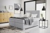 Modernes weißes Boxspringbett im Schlafzimmer mit grauem Teppich und minimalistischer Deko.