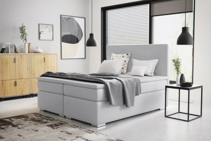 Modernes weißes Boxspringbett im Schlafzimmer mit grauem Teppich und minimalistischer Deko.