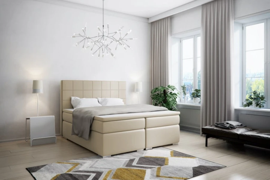 Beiges Boxspringbett mit quadratischer Steppung im Kopfteil in einem hellen, stilvollen Raum.