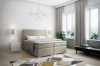 Modernes Boxspringbett in Beige in einem hellen, stilvollen Schlafzimmer mit Teppich und Pflanzen.