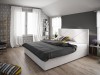 Modernes weißes Boxspringbett mit dekorativem Kopfteil im Schlafzimmer.