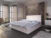 Elegantes Boxspringbett in Weiß mit Knopftufter-Kopfteil vor einer dunklen Betonoptik-Wand.