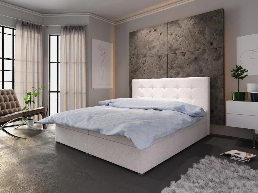 Elegantes Boxspringbett in Weiß mit Knopftufter-Kopfteil vor einer dunklen Betonoptik-Wand.