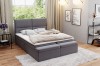 Gemütliches graues Boxspringbett mit gepolstertem Kopfteil und passender Bettbank im Schlafzimmer.