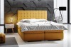 Modernes gelbes Boxspringbett mit gestepptem Kopfteil im stilvoll eingerichteten Schlafzimmer.
