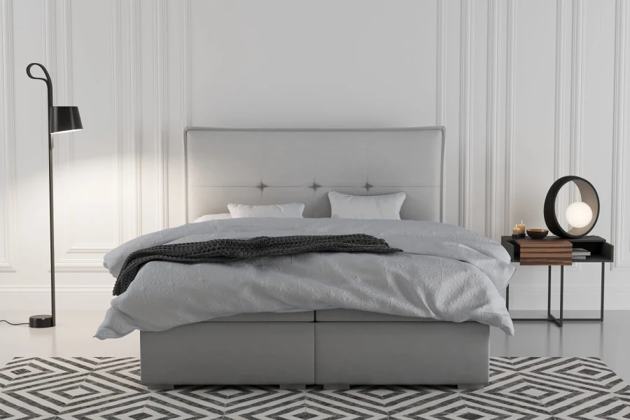 Modernes hellgraues Boxspringbett mit dekorativem Kopfteil im Schlafzimmer.