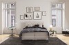 Modernes Schlafzimmer mit hellem Boxspringbett und dekorativer Wand.