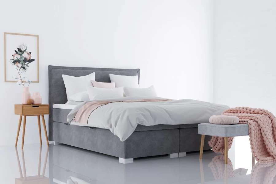 Graues Polsterbett im modernen Schlafzimmer mit Nachttisch und rosa Wolldecke.