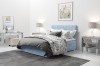 Hellblaues Boxspringbett mit floraler Bettwäsche in modernem Schlafzimmer.