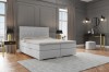 Hellgraues Boxspringbett mit gestepptem Kopfteil in stilvollem Schlafzimmer-Ambiente.