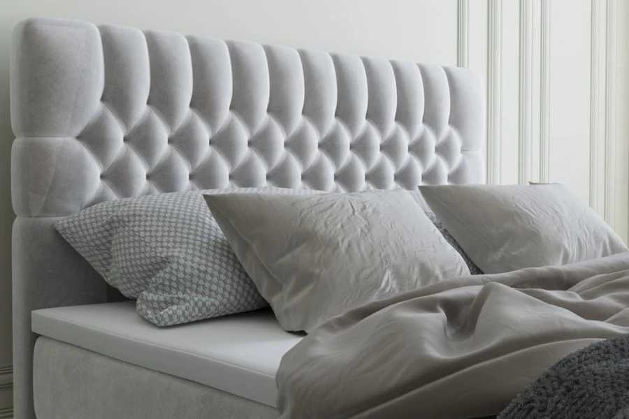 Detailaufnahme eines grauen, gesteppten Bett-Kopfteils aus Samt in Chesterfield-Optik.