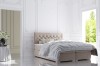 Elegantes Boxspringbett in Beige mit gestepptem Kopfteil in einem hellen, klassischen Schlafzimmer.