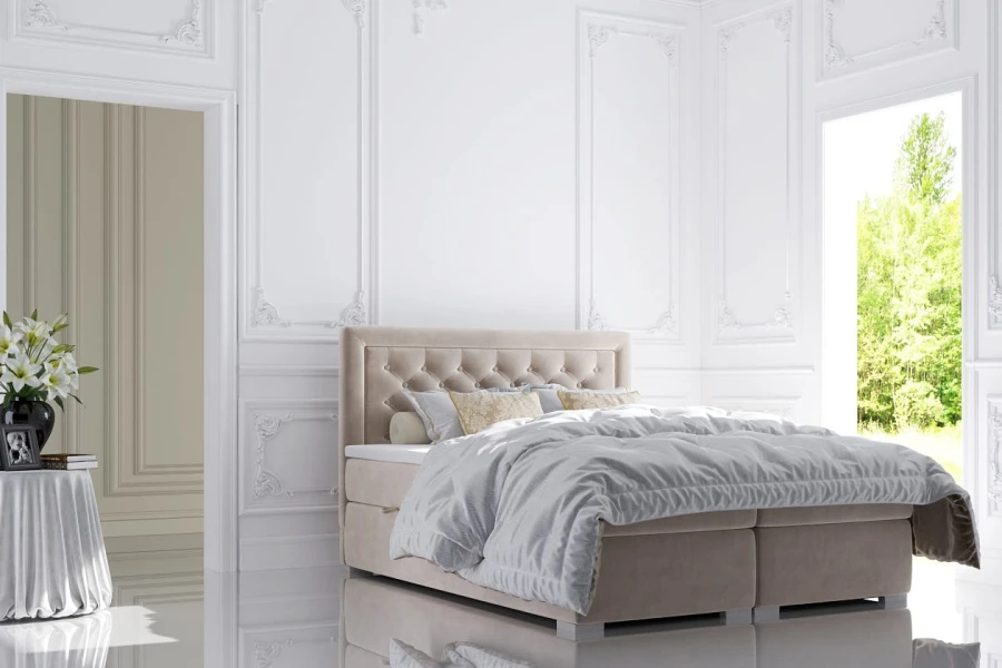 Elegantes Boxspringbett in Beige mit gestepptem Kopfteil in einem hellen, klassischen Schlafzimmer.