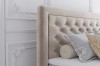 Nahaufnahme eines gepolsterten Kopfteils mit Chesterfield-Steppung in Beige.