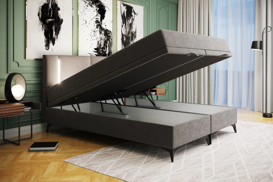 Graues Polsterbett mit seitlich aufgeklapptem Bettkasten für praktischen Stauraum im Schlafzimmer.