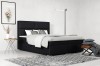 Modernes Boxspringbett in Schwarz mit gepolstertem Kopfteil im hellen Schlafzimmer.