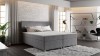 Graues Boxspringbett in einem modernen Schlafzimmer mit Backsteinwand und Loft-Stil.