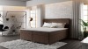 Braunes Boxspringbett in modernem Schlafzimmer mit weißer Backsteinwand.