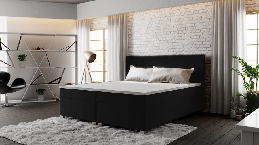 Modernes schwarzes Boxspringbett vor weißer Backsteinwand im Schlafzimmer.