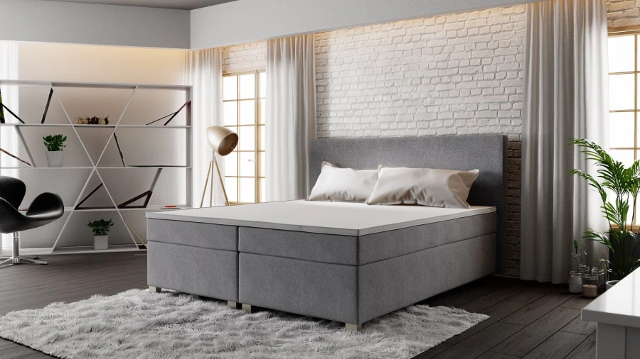 Elegantes graues Boxspringbett mit weißem Topper im modernen Wohnambiente.