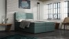 Modernes Boxspringbett in Türkis mit gestepptem Kopfteil vor weißer Backsteinwand.