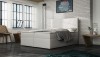 Weißes Boxspringbett vor weißer Ziegelwand im Industriedesign-Stil.