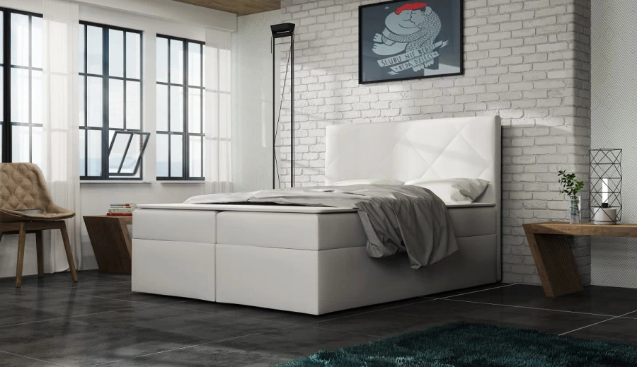 Weißes Boxspringbett vor weißer Ziegelwand im Industriedesign-Stil.
