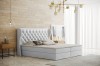 Weißes Boxspringbett mit gestepptem Kopfteil in modernem Schlafzimmer-Design.