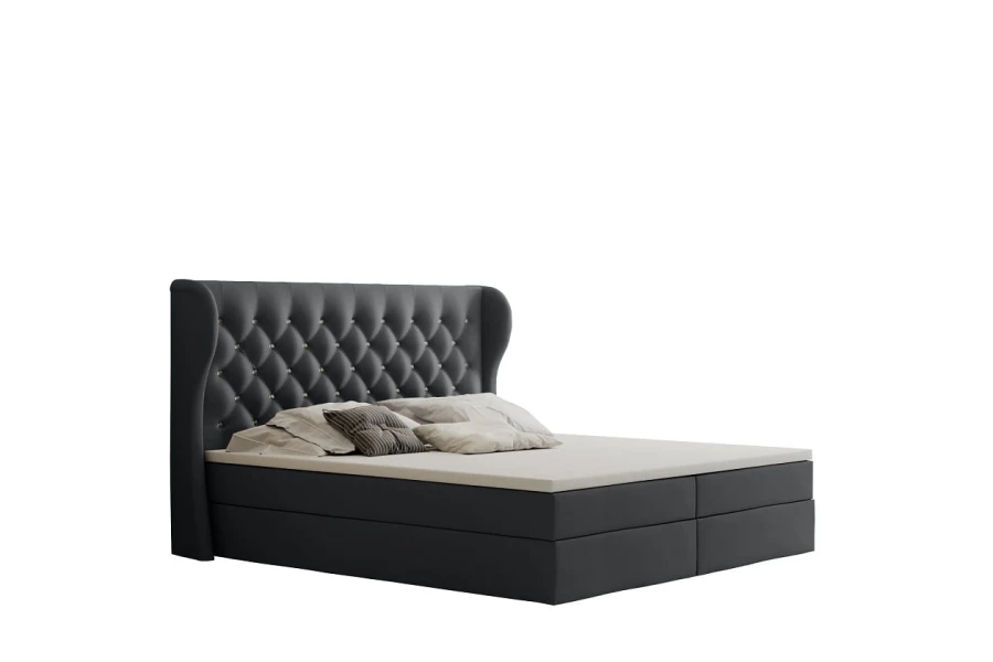 Dunkelgraues Boxspringbett mit gestepptem Kopfteil vor weißem Hintergrund.