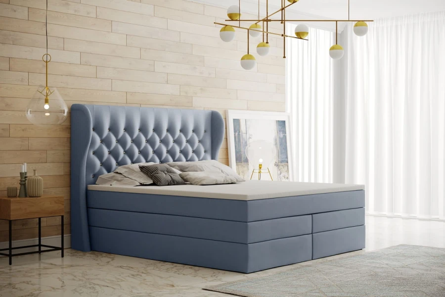 Hellblaues Boxspringbett mit elegantem Kopfteil und Knopfheftung vor einer hellen Holzwand.