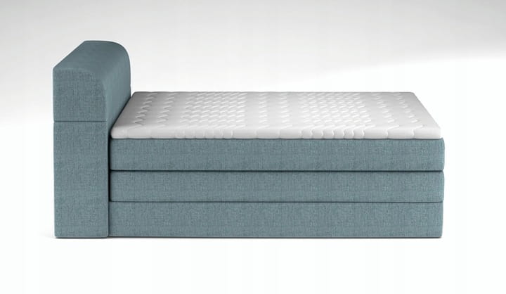 Direkte Seitenansicht eines hellblauen Boxspringbetts mit hohem, gepolstertem Kopfteil.