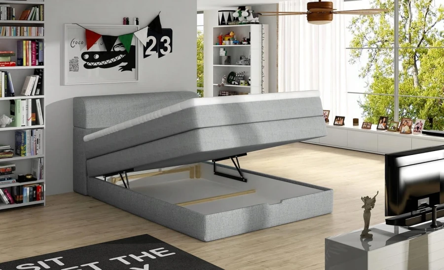 Graues Boxspringbett mit seitlich aufgeklapptem Bettkasten für zusätzlichen Stauraum.