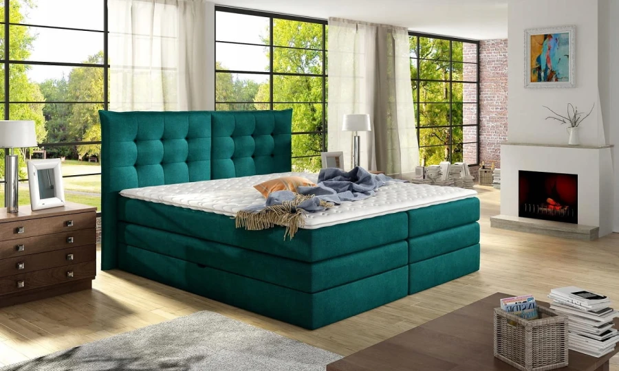 Petrolfarbenes Boxspringbett mit Knopfsteppung am Kopfteil in edlem Wohnambiente mit Kamin.