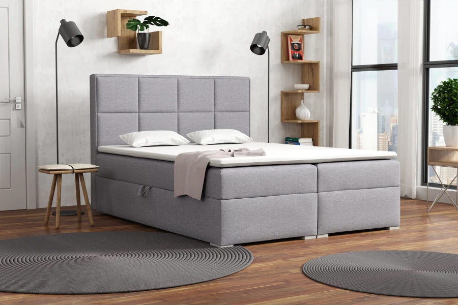 Hellgraues Boxspringbett in einem modern eingerichteten Schlafzimmer.