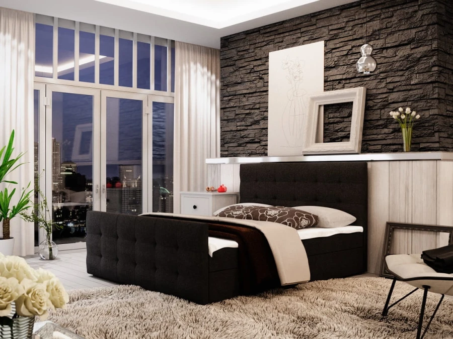 Dunkelgraues Boxspringbett mit Knopfsteppung vor einer markanten dunklen Steinwand.