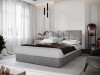 Hellgraues Boxspringbett mit elegantem Kopfteil und weißer Bettwäsche.
