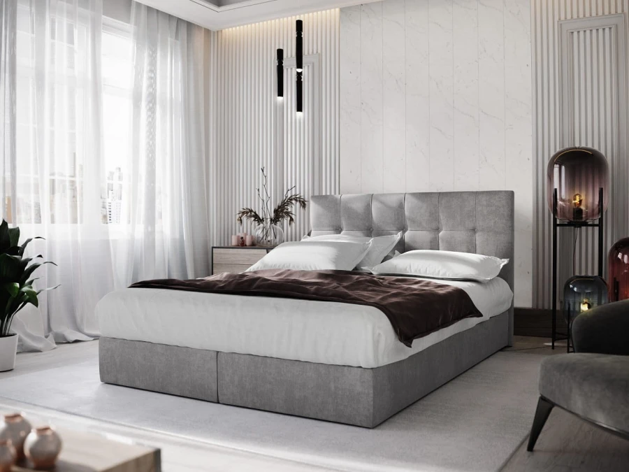 Hellgraues Boxspringbett mit elegantem Kopfteil und weißer Bettwäsche.