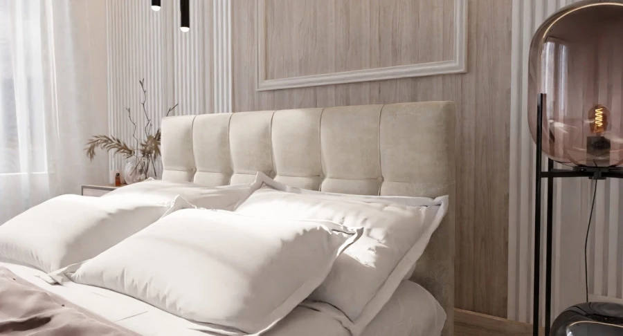 Nahaufnahme eines beige gepolsterten Kopfteils mit quadratischer Steppung und weißen Kissen.