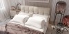 Beige Boxspringbett mit weißen Kissen, brauner Decke und modernen Glasleuchten im Schlafzimmer.